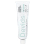 Davids silver metal tube roller key being used to squeeze a peppermint toothpaste tube on a white background.