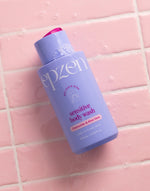 Creamy texture of Epzen Sensitive Body Wash being applied to a person's hand under running water.