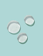 Close-up of clear Epzen Body Wash being poured onto a white surface, showing its smooth, gel-like texture.