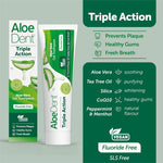 Close-up of an Aloe Dent Triple Action Toothpaste tube being squeezed onto a bamboo toothbrush.