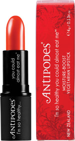 Antipodes West Coast Sunset Lipstick in a black tube, featuring a vibrant orange-red shade on a white background.