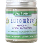 Auromere Fresh Mint Ayurvedic toothpaste in a glass jar with a metal lid and a small wooden spoon on a white background.