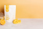 250g tub of Happy Way Tropical Marine Collagen Powder on a vibrant blue and orange background with tropical fruit.