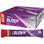 Box of 18 CLIF Bloks Mountain Berry energy chew packets with a sample chew and mountain biking imagery.