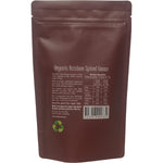 150g bag of Organic Rainbow Spiced Cacao Chai Tea with raw cacao and spices on a white background.