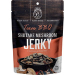 12ct box of DJ&A Shiitake Mushroom Jerky Texas BBQ 60g packs with plant-based and high-fiber logos on a white background.