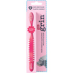 Close-up of a pink Grin kids' recycled toothbrush with extra soft white bristles and a non-slip handle.