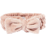 Soft blush pink spa headband with a decorative bow, displayed on a white background.