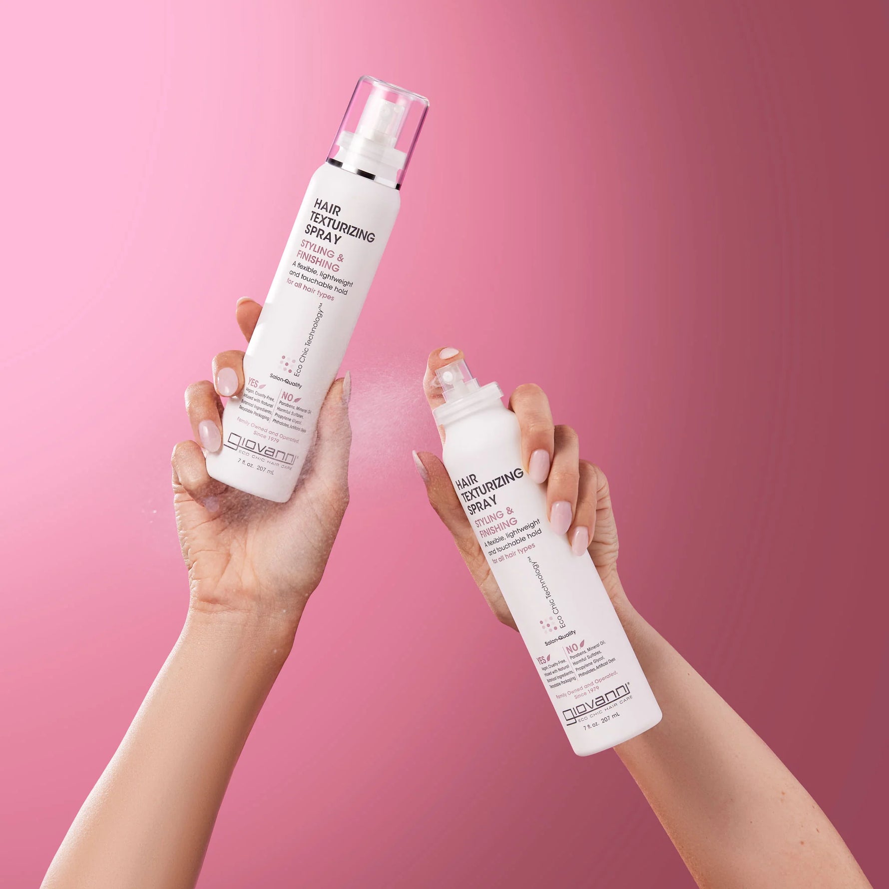 A person sprays Giovanni Hair Texturizing Spray onto their long, wavy blonde hair for volume and definition.