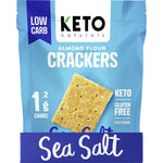 Top view of circular, golden-brown Keto Naturals Sea Salt Almond Flour Crackers scattered on a white background.