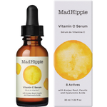 Mad Hippie Vitamin C Serum in an amber glass dropper bottle next to its white packaging box, both featuring a yellow watercolor circle graphic.