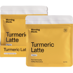 Morning Made Turmeric Latte box next to a prepared golden latte, a single sachet, and scattered spices on a white surface.