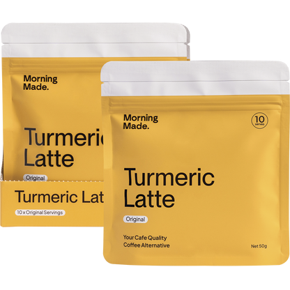 Morning Made Turmeric Latte box next to a prepared golden latte, a single sachet, and scattered spices on a white surface.