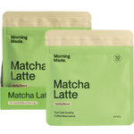 Vanilla Matcha Latte box, sachet, and a frothy green drink in a glass with a gold spoon on a white background.