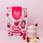 Scoop of White Choc Raspberry Whey Protein Powder with fresh raspberries and white chocolate pieces on a white background.