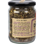 Mindful Foods DMTea 100g glass jar with an orange label, showcasing organic herbal tea ingredients inside.