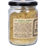 Mindful Foods yeast flakes in a glass jar with a black and gold label against a white background.