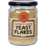100g glass jar of Mindful Foods fortified and toasted yeast flakes with a black and gold label.