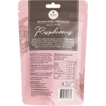 Dark chocolate-coated freeze-dried raspberries held in a hand with a whole fresh raspberry on a white background.