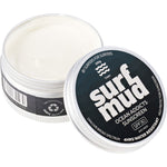 Open tin of Surfmud SPF 30 sunscreen showing the white cream inside next to its lid on a white background.