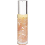 Essential oil roller with rose quartz crystals and 24K gold flakes, featuring a clear glass bottle and pink cap.