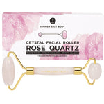 Rose quartz facial roller with a matching pink pouch and floral-patterned gift box on a clean white background.