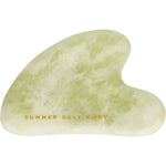 Heart-shaped green jade Gua Sha stone with smooth, polished edges on a white background.