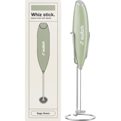 Sage green Switch Nutrition Whiz Stick electric handheld mixer with a silver whisk attachment and a matching storage stand.