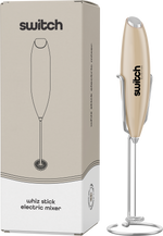 Beige Switch Nutrition Whiz Stick electric mixer shown with its storage stand and product packaging.
