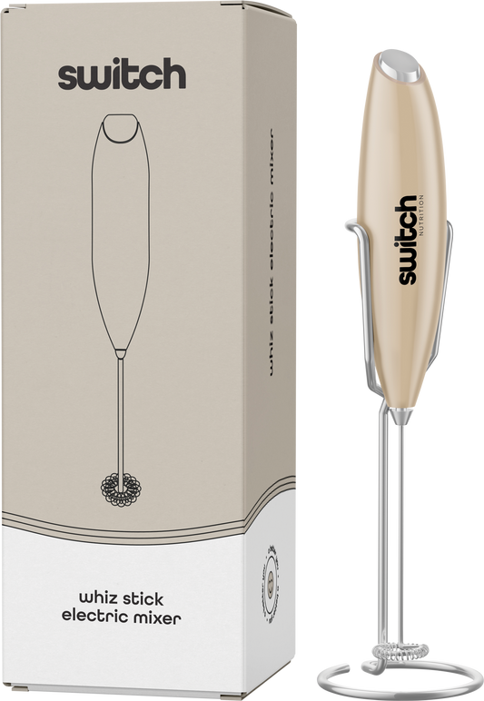 Beige Switch Nutrition Whiz Stick electric mixer shown with its storage stand and product packaging.
