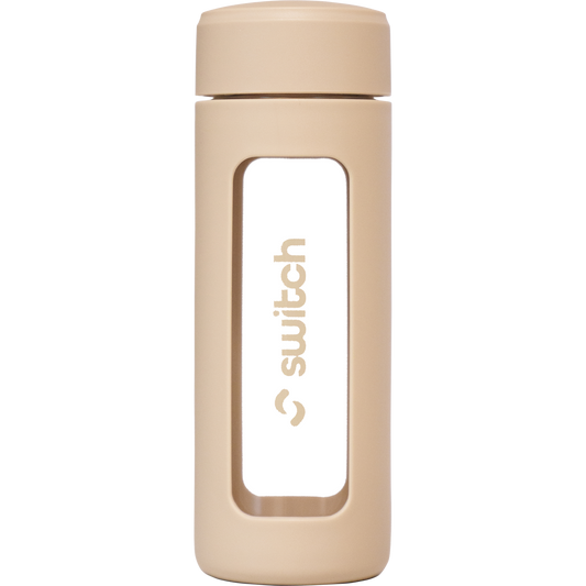 Switch Nutrition 460ml glass water bottle with a beige silicone sleeve and a built-in tea strainer.