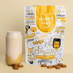 A 500g bag of Happy Way Salted Caramel Vegan Protein Powder next to a glass of smoothie with a straw.
