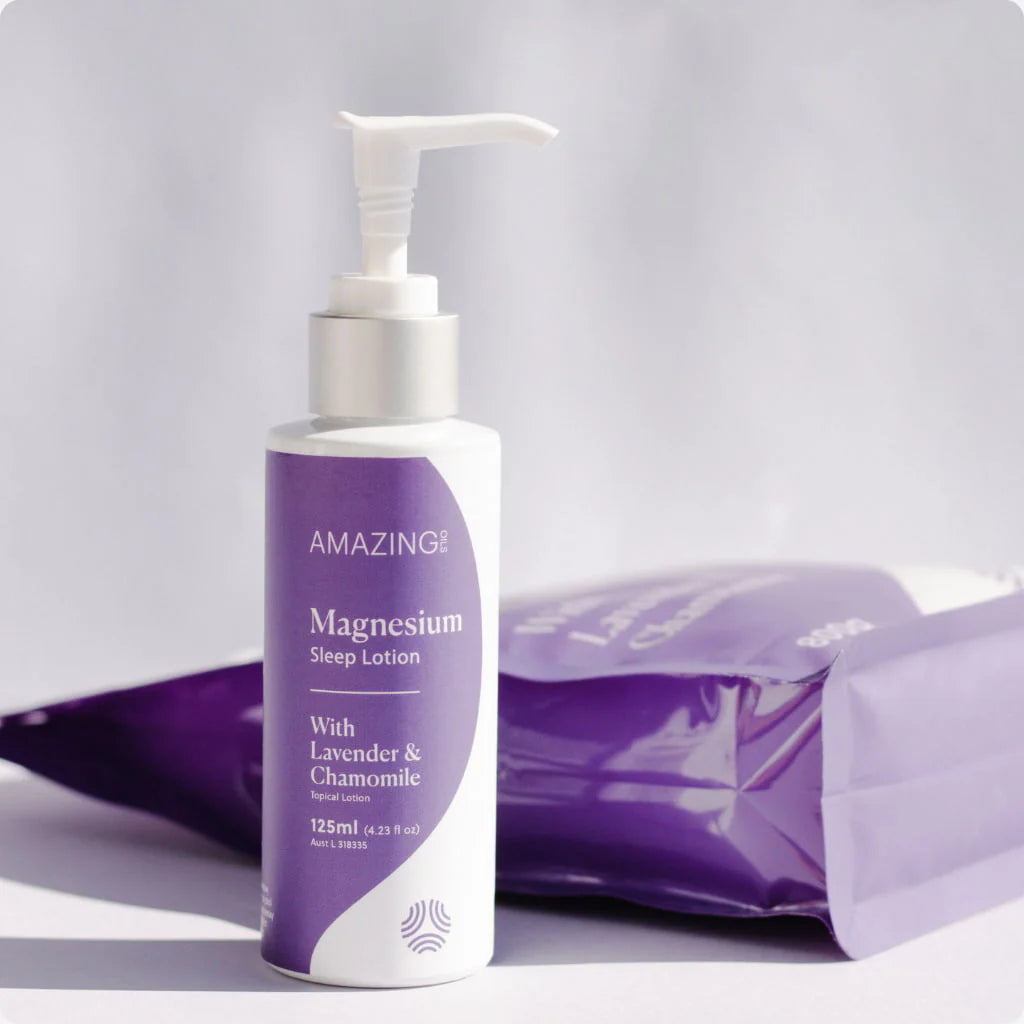 A 200ml bottle of Amazing Oils Magnesium Sleep Lotion with dried lavender and chamomile flowers on a white background.