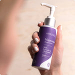 Close-up of a hand applying white Amazing Oils Magnesium Sleep Lotion to a person's foot against a white background.