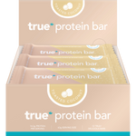 Open box of True Protein Toasted Coconut Bars showing 12 individually wrapped 63g bars in blue and white packaging.