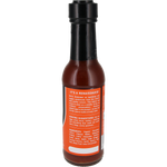 A bottle of hot sauce with a black cap and a bright orange label, photographed on a plain white background. The label contains white text and lists ingredients including tomato paste, vinegar, garlic, and black pepper.