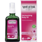 Weleda Harmonising Body Oil Wild Rose 100ml bottle standing next to its pink and white cardboard packaging.