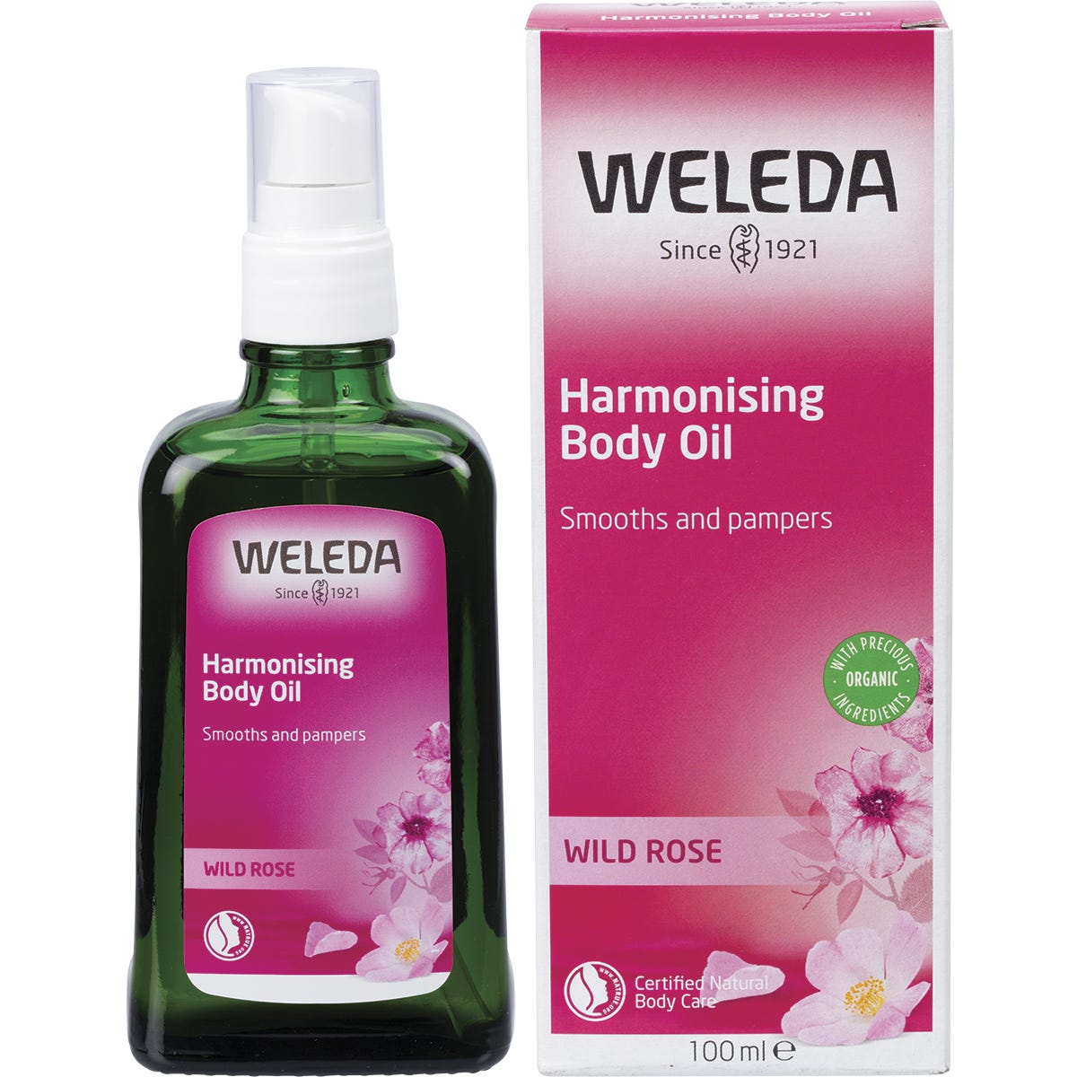 Weleda Harmonising Body Oil Wild Rose 100ml bottle standing next to its pink and white cardboard packaging.