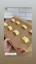 Golden-brown EveryMite and cheese scrolls on a cooling rack, showing a swirl of savory black sesame spread and melted cheese.