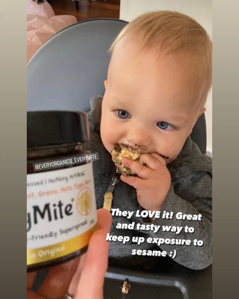 A happy young boy eating a slice of toast with EveryMite Original savory spread.