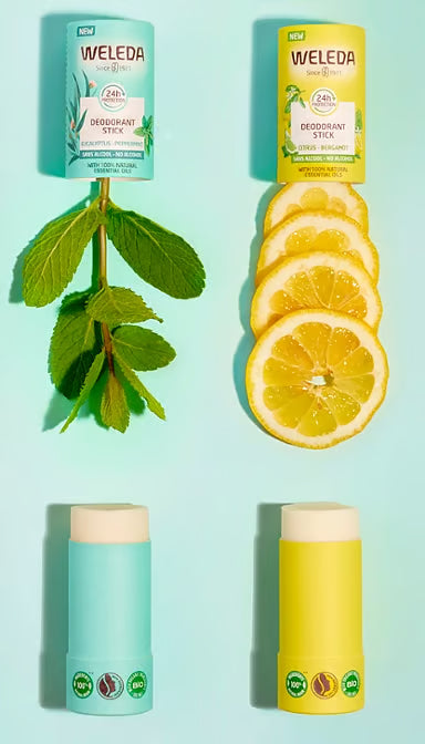 Flat lay of Citrus and Eucalyptus Weleda deodorant sticks with fresh lemon, bergamot, and eucalyptus leaves.