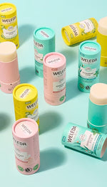 A group shot of four open Weleda deodorant sticks in cardboard tubes, showing the smooth, solid product inside.
