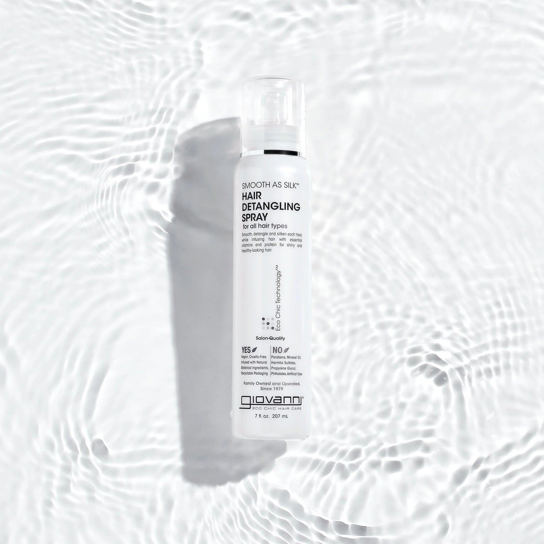 Close-up of long, wet brunette hair being sprayed with a fine mist of Giovanni detangling spray.