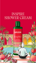 Weleda Inspire Pomegranate Shower Cream 400ml bottle with sliced pomegranates and flowers on a white background.