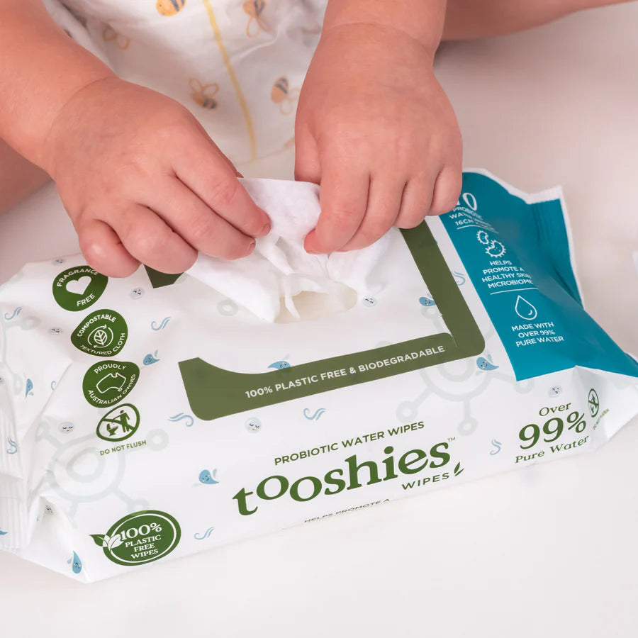 Close-up of a Tooshies Probiotic Water Wipe being pulled from a white and blue flip-top pack.
